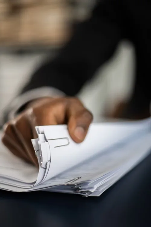 Homeowner holding a stack of insurance policy documents clipped together