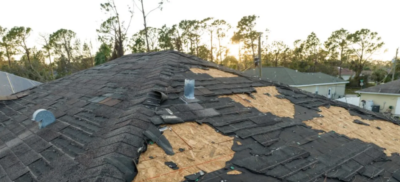 Storm-damaged roof with missing shingles on a Missouri home