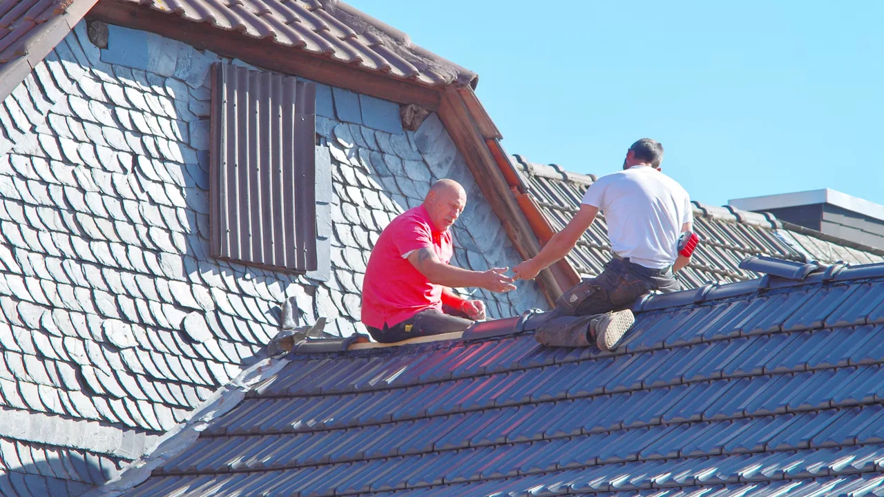 Two roofers documenting storm damage on a residential roof