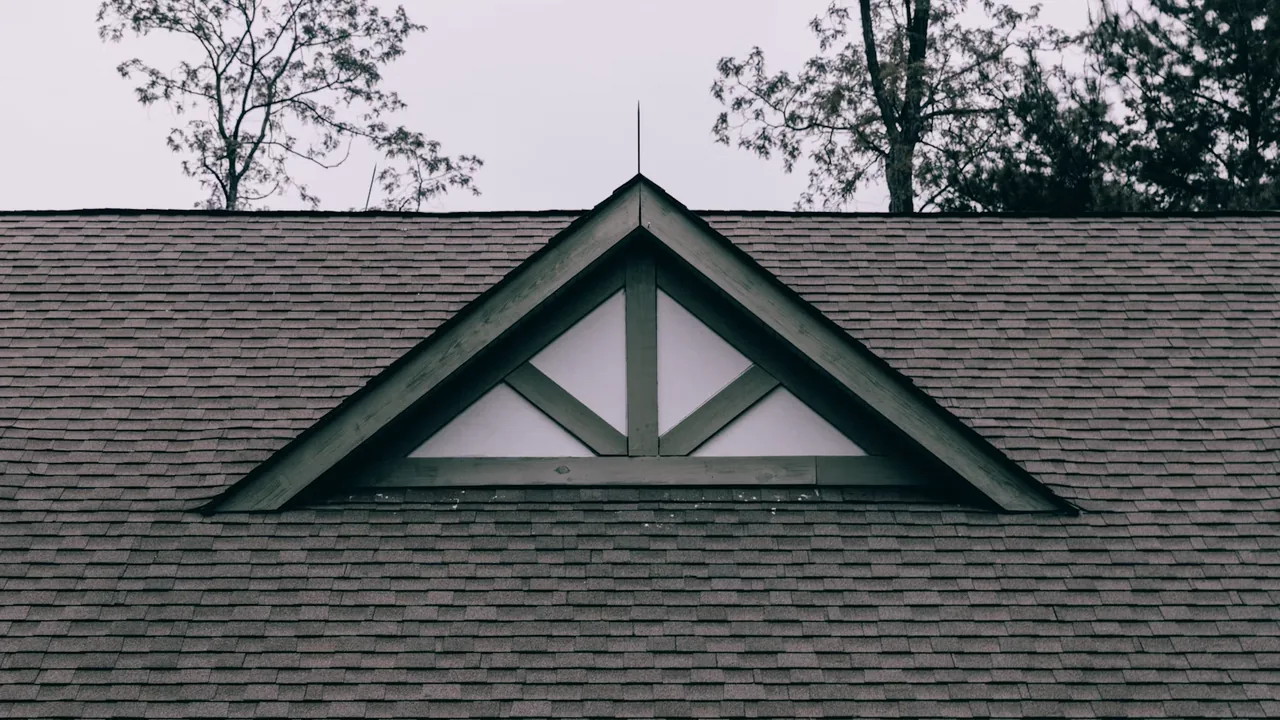 Residential roof with a gabled dormer window under an overcast Missouri sky