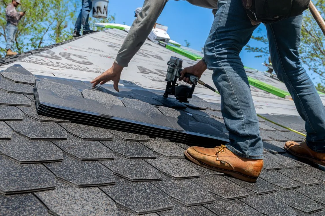 Roofing crew installing shingles on a residential roof
