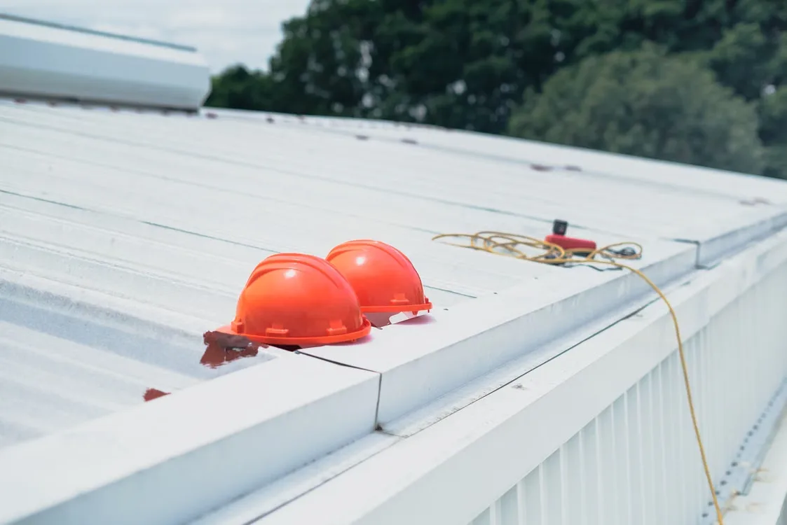 Two orange hard hats resting on a rooftop during a post-storm roof inspection